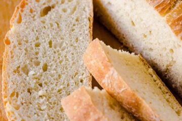 Artisan Bread slices on a cutting board with loaf of no-knead bread
