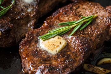 Pan-Seared Steak on skillet topped with butter and fresh rosemary