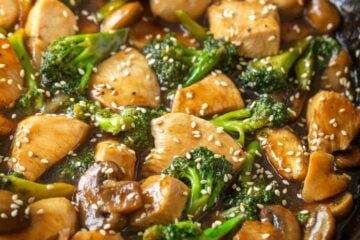 Chicken and broccoli stir fry in skillet garnished with sesame seeds