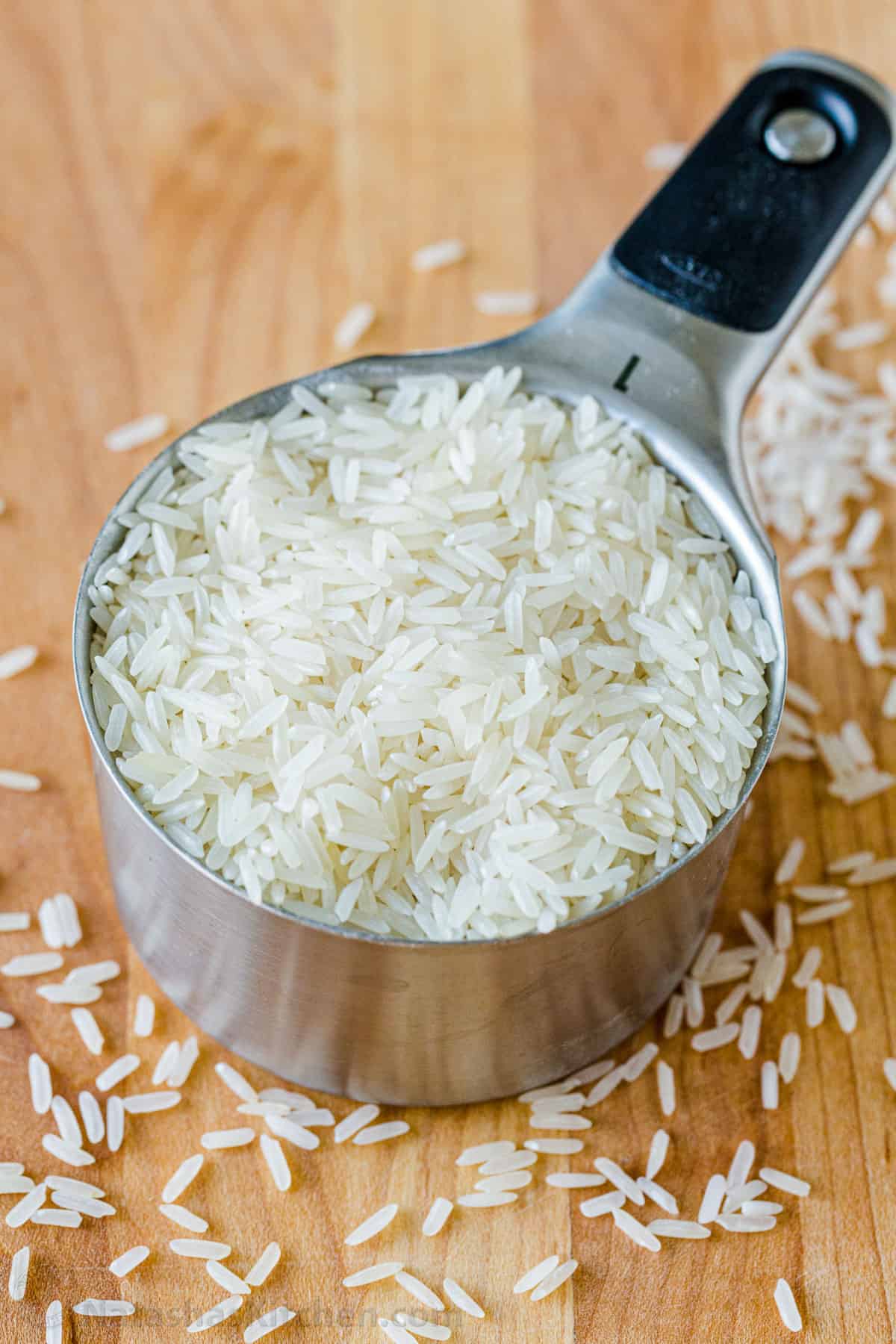 Jasmine white long grain rice in a measuring cup with rice surrounding the base