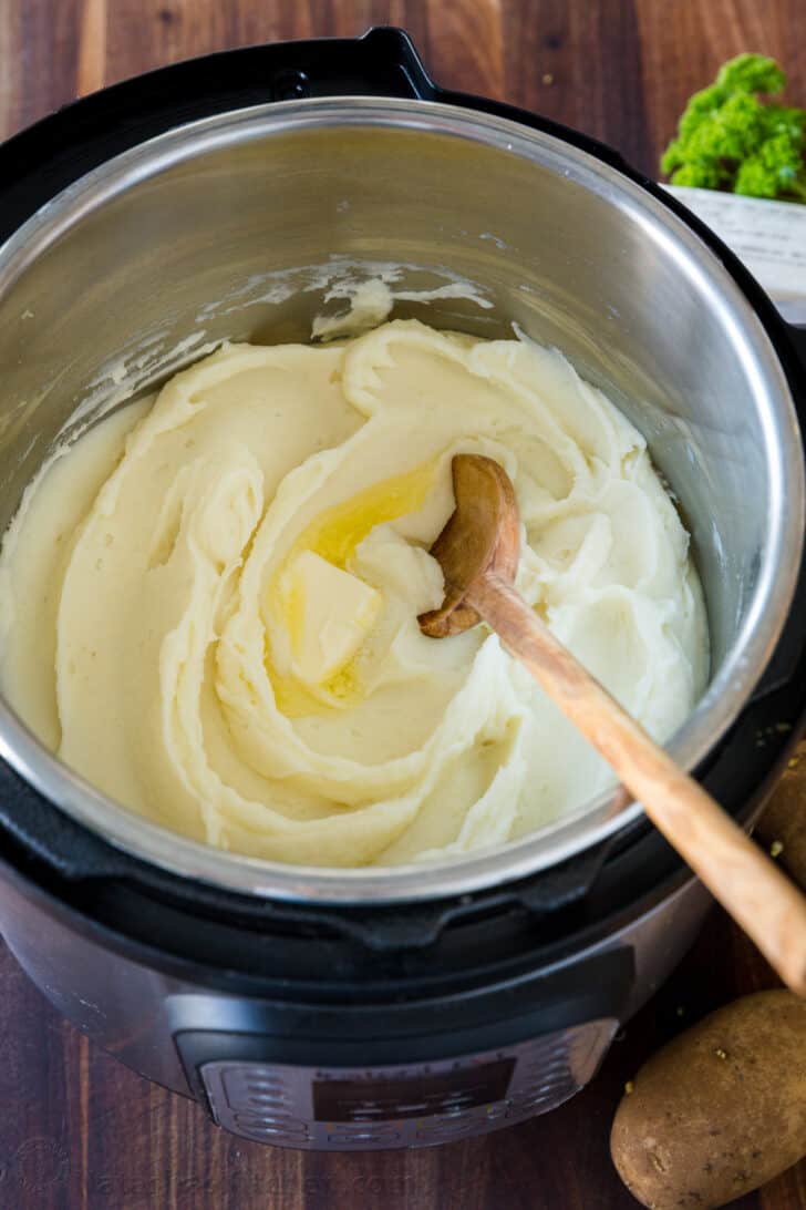 Creamy mashed potatoes inside the bowl of an insta pot topped with butter