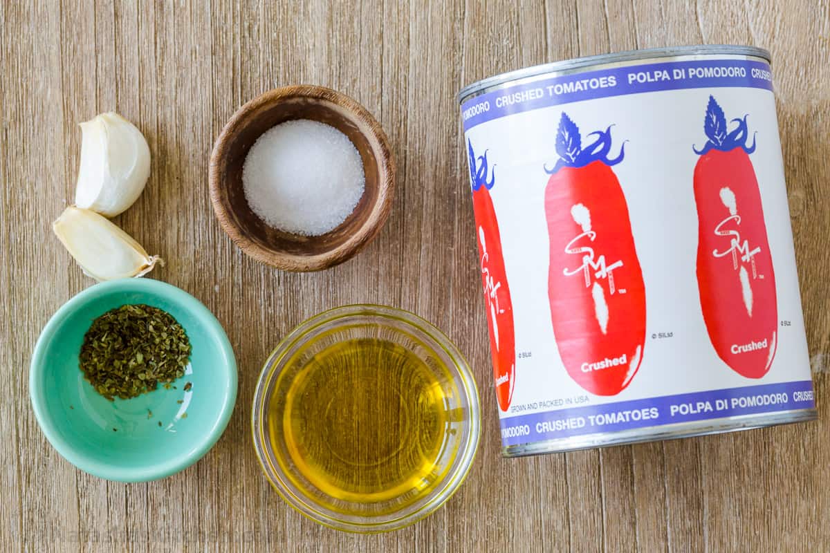 Ingredients for blending breadstick dip with crushed tomatoes, olive oil, garlic, salt and oregano. 