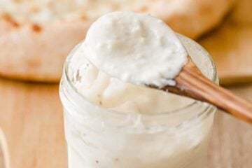 White pizza sauce on a spoon and in mason jar