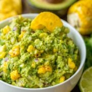 Grilled corn guacamole in a bowl with a tortilla chip