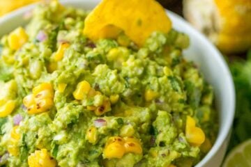 Grilled corn guacamole in a bowl with a tortilla chip