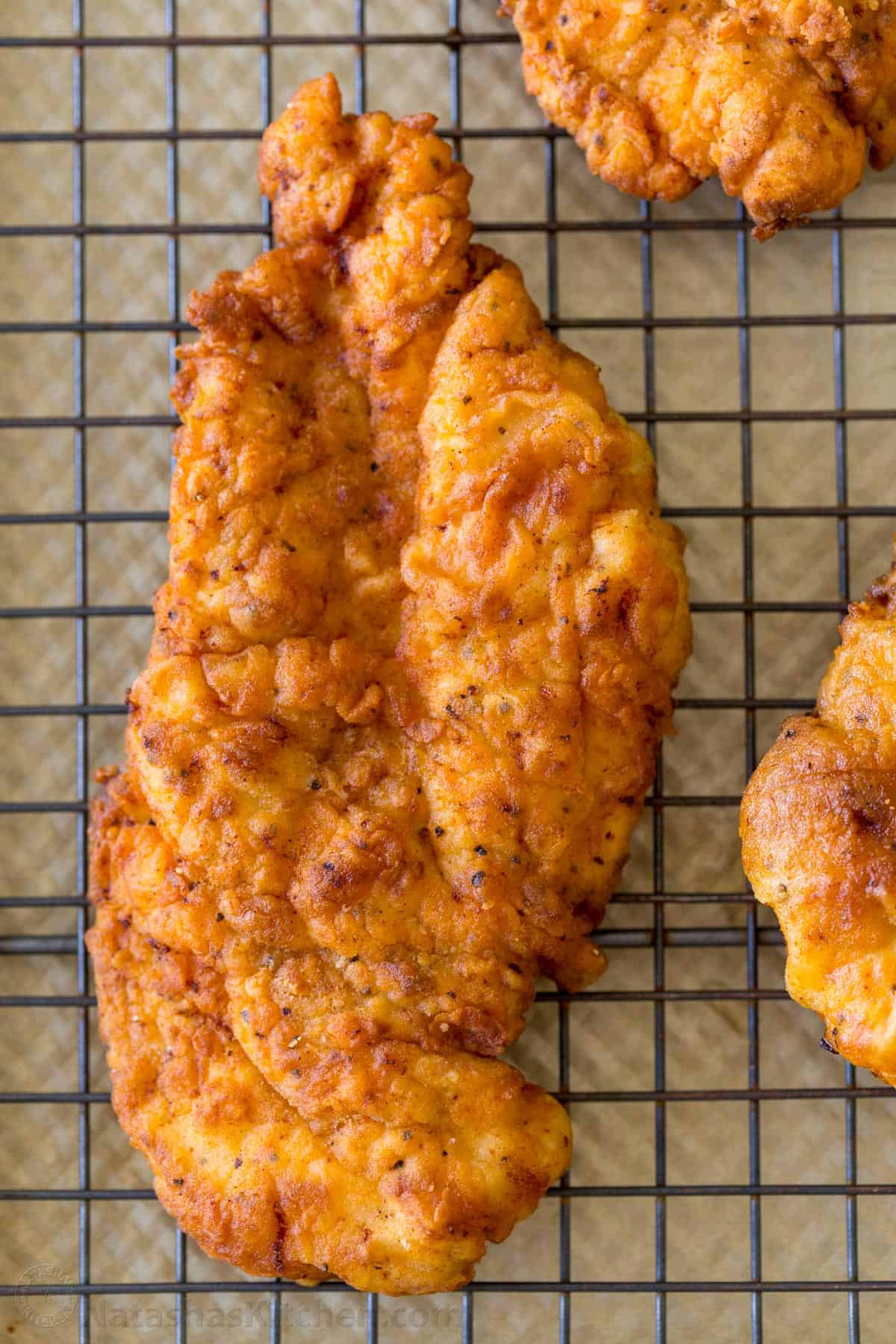 Fried crispy chicken breast patty on a wire rack