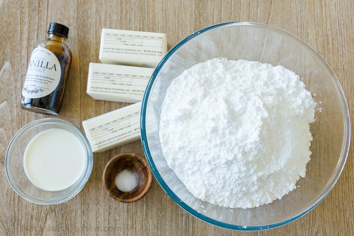 Ingredients for making vanilla buttercream frosting including vanilla, heavy cream, salt, unsalted butter and powdered sugar
