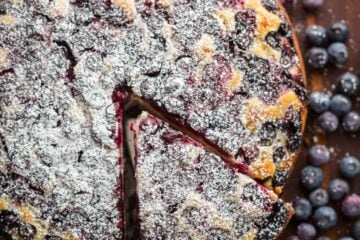 Lemon Blueberry Cake dusted with powdered sugar and slice cut out