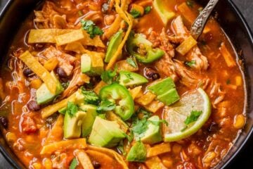 chicken Tortilla Soup garnished with avocado, cilantro and lime