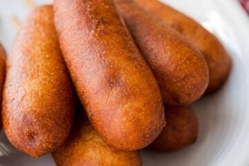 homemade corn dogs on a serving plate with ketchup and mustard
