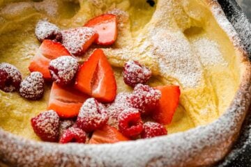 Dutch baby topped with fruit and powdered sugar