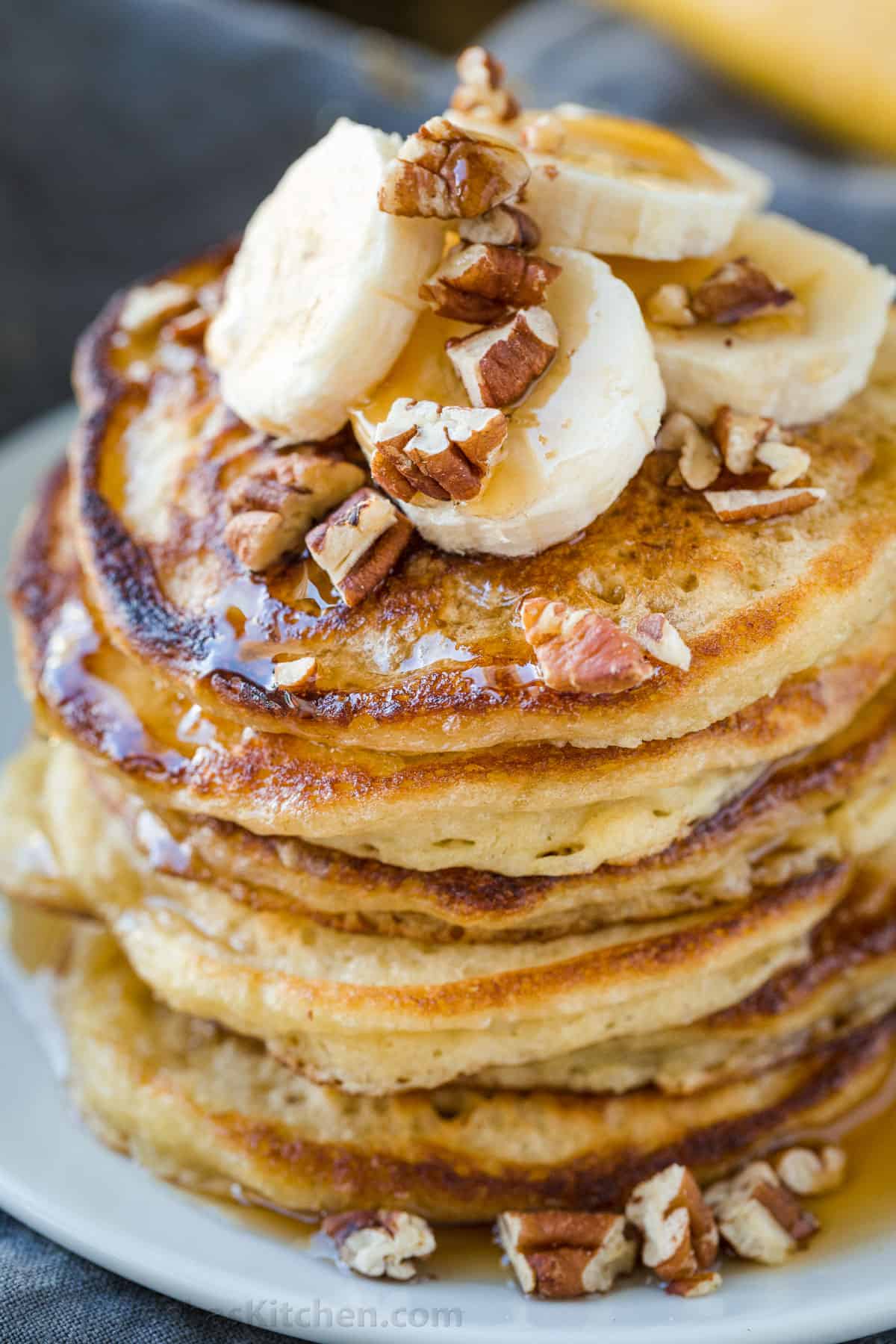 My Banana Pancakes recipe uses ripe bananas for a fluffy breakfast. Bake now or mix the night before for speedy cooking in the morning. Stacked banana pancakes topped with bananas, pecans and maple syrup
