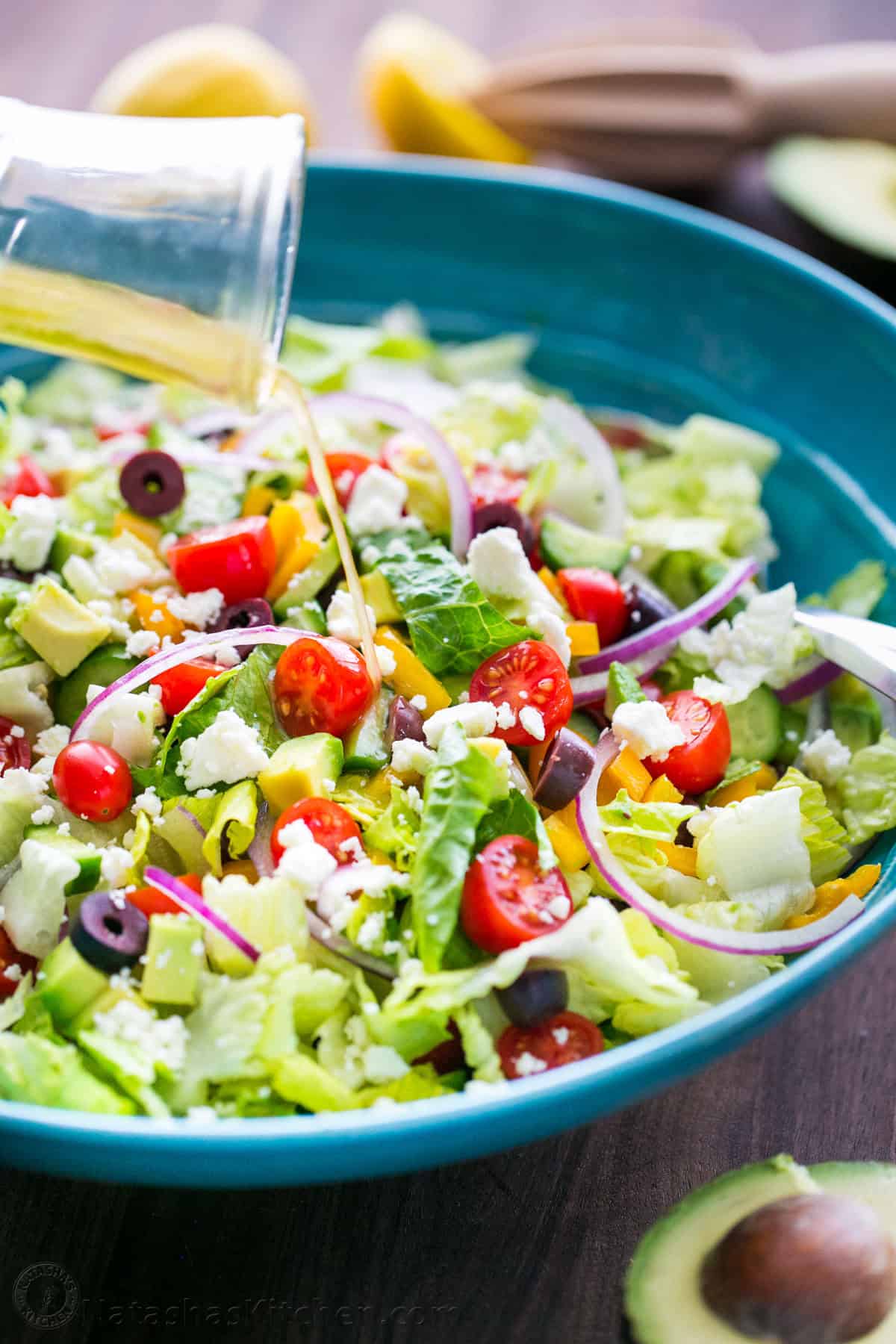 Pouring Greek Salad Dressing over Chopped Greek Salad