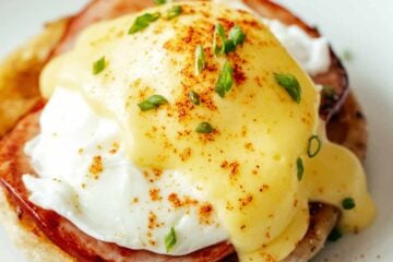 Eggs Benedict on a plate topped with hollandaise