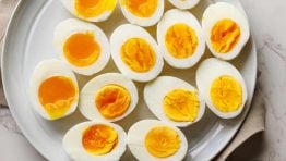 Boiled eggs cut in half at varying doneness with soft boiled and hard boiled eggs on a platter.