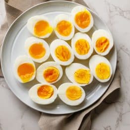 Boiled eggs cut in half at varying doneness with soft boiled and hard boiled eggs on a platter.