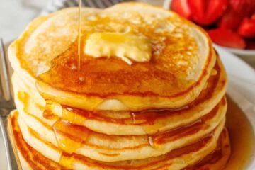 Buttermilk Pancakes stacked on a plate served with maple syrup