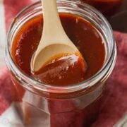 Closeup of barbecue sauce in jar with wooden spoon