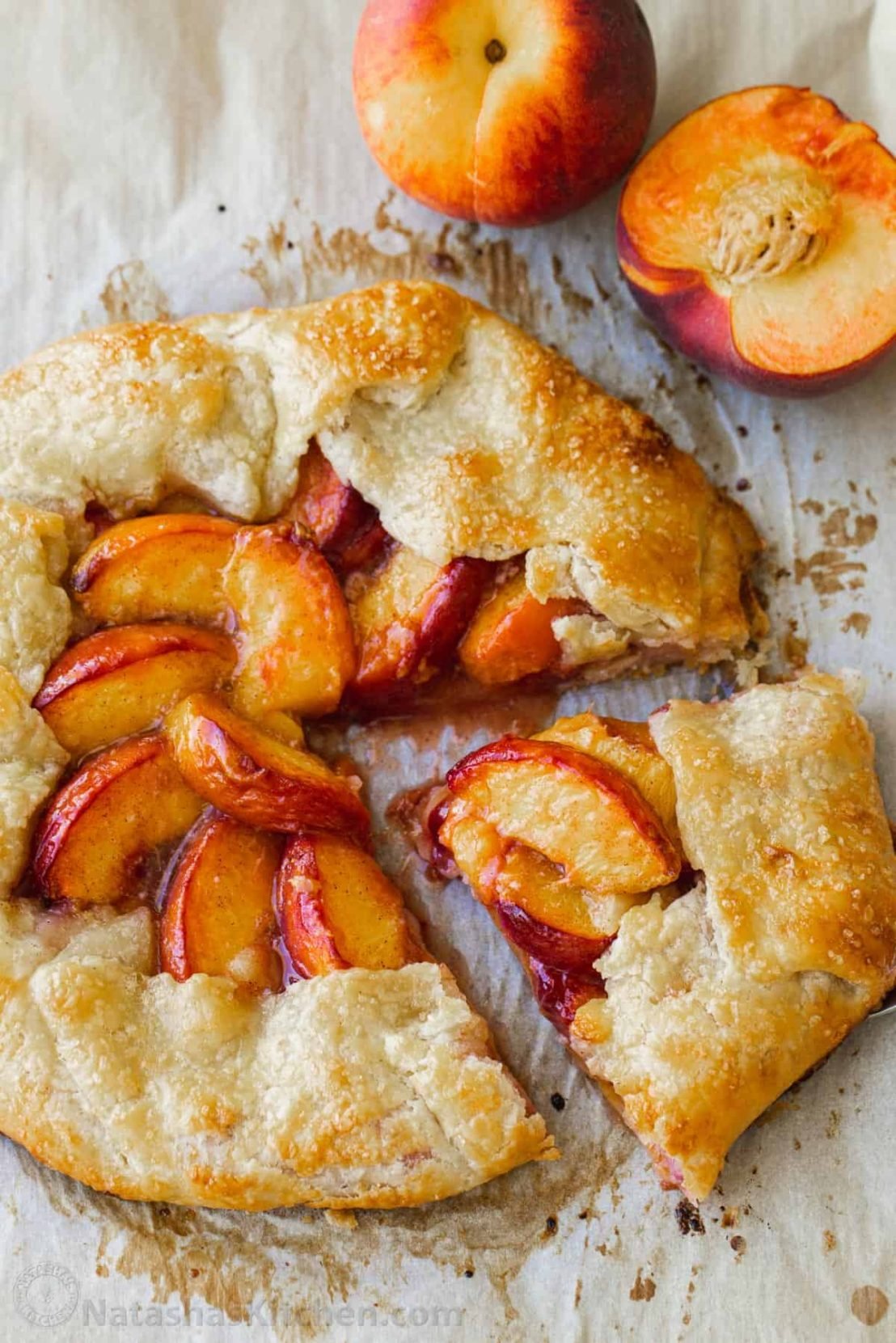 Peach galette on parchment paper with fresh peaches