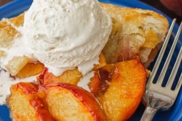Peach galette on blue plate, topped with scoop of ice cream