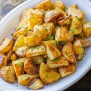Perfect roasted potatoes in a white serving dish, garnished with parsley.