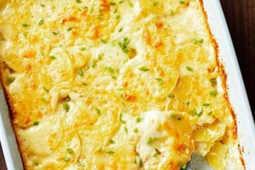 Golden baked au gratin potatoes in a rectangular baking dish with a scoop missing.