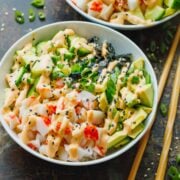 A California roll bowl topped with a drizzle of spicy mayo next to chopsticks.