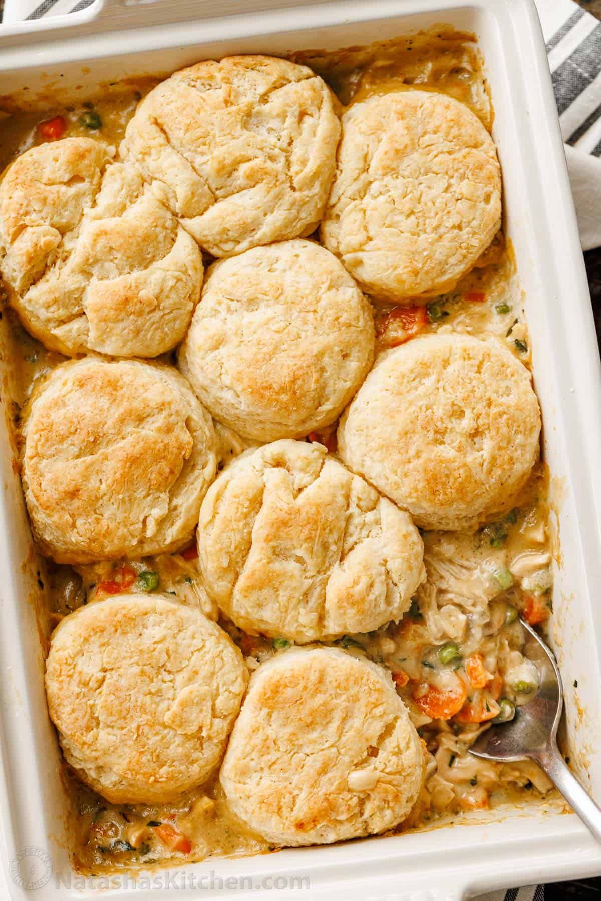 Chicken Pot Pie Casserole has all the same cozy flavors we love, but it's so easy to bake in a casserole dish, topped with flaky biscuits. chicken pot pie casserole with one portion removed on serving spoon