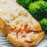 Air fryer salmon fillet on a white plate served with a side of rice and broccoli.