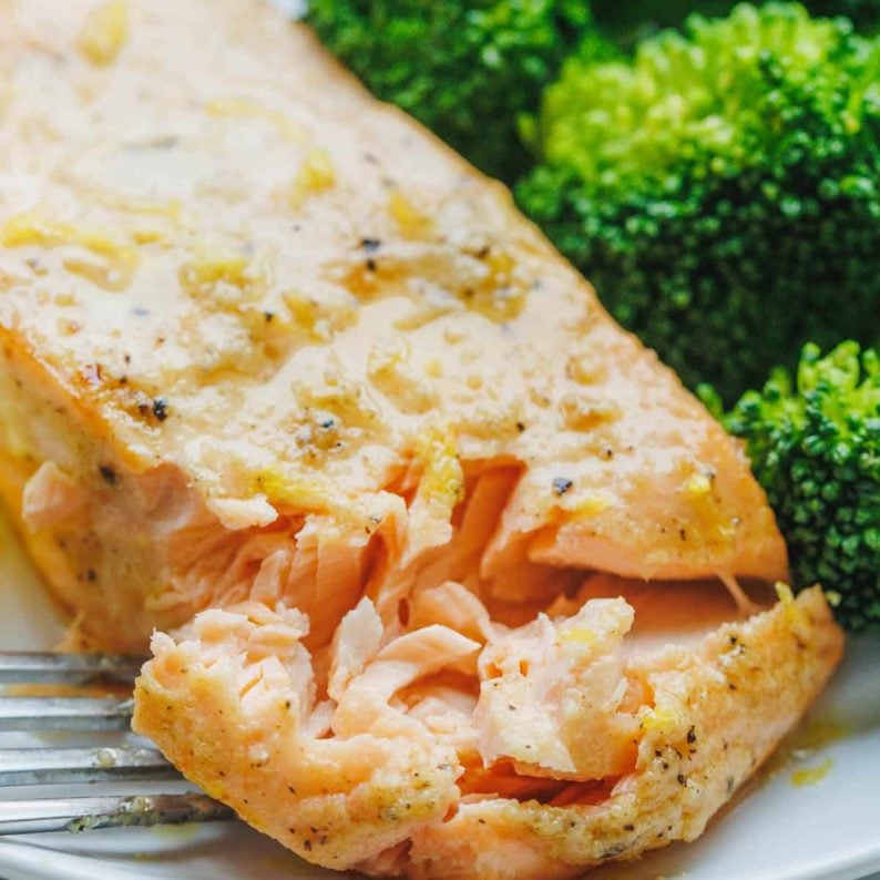 Air fryer salmon fillet on a white plate served with a side of rice and broccoli.