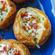 Baked Potato on a blue plate topped with bacon and sour cream