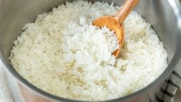 Perfectly cooked fluffy white rice in a saucepan with a serving spoon
