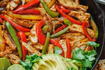 Chicken fajitas served in a skillet with avocado and cilantro