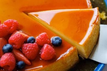 Flan dessert served on a cake platter with berries