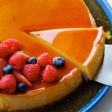 Flan dessert served on a cake platter with berries