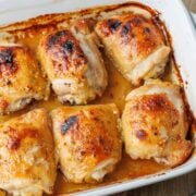 Overhead view of baked honey mustard chicken thighs in a ceramic casserole dish.