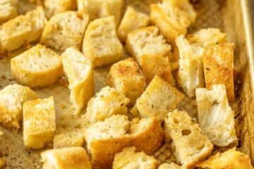 Homemade croutons on a metal baking sheet.