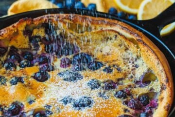 blueberry lemon dutch baby in skillet with powdered sugar sprinkled on top