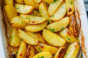 Sliced potato wedges in casserole dish garnished with oregano