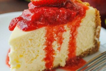 strawberry cheesecake sliced on a plate with strawberry sauce topping