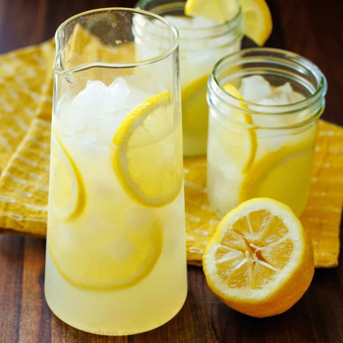 Lemonade served in a carafe with yellow towel and lemon rounds