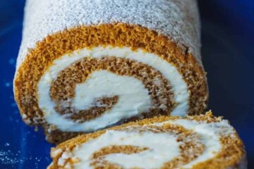 Pumpkin Roll Cake with powdered sugar and a slice