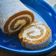 A slice of pumpkin roll cake with cream cheese filling and powdered sugar