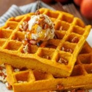 Pumpkin waffles stacked with whipped honey butter, toasted pecans, and maple syrup