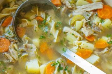 Hearty turkey noodle soup being scooped out of a pot with a large ladle