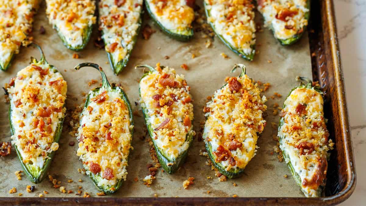 This easy jalapeño poppers recipe is so tasty with cheesy filling, crispy topping and homemade bacon bits. This fun appetizer goes fast! jalapeno poppers with crunchy topping on a lined sheet pan