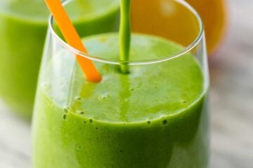 Green smoothie recipe poured into a cup with a straw