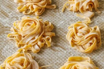 homemade pasta dough in nests on a baking sheet