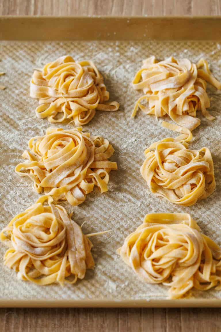 homemade pasta dough in nests on a baking sheet