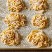 nests of homemade pasta dough dusted with flour on a sheet pan